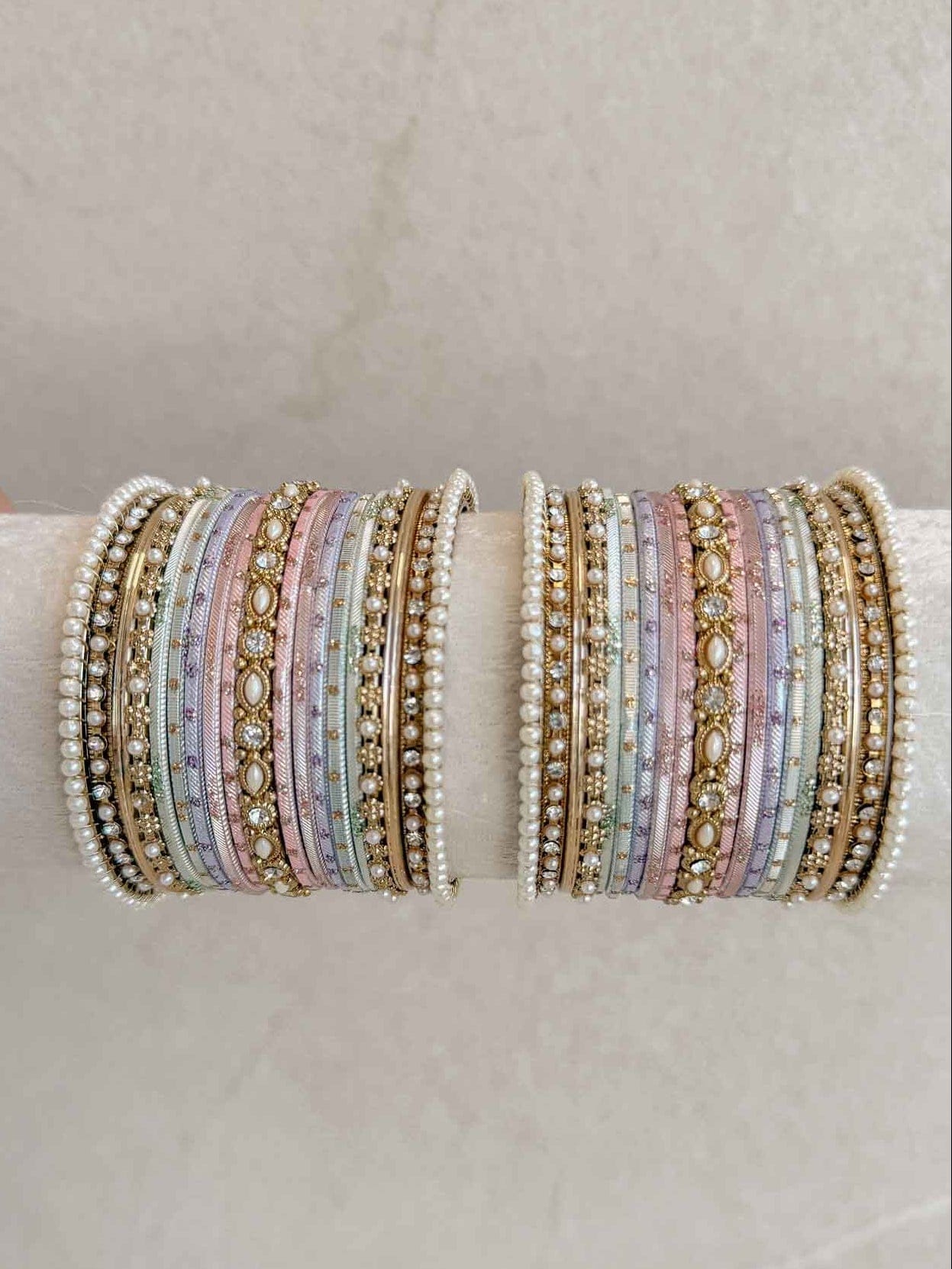 Set of multicolored pastel beaded bracelets on a beige surface with 'SokoraJewels.com' branding.