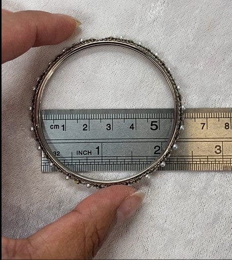 Silver bangle being measured with a ruler